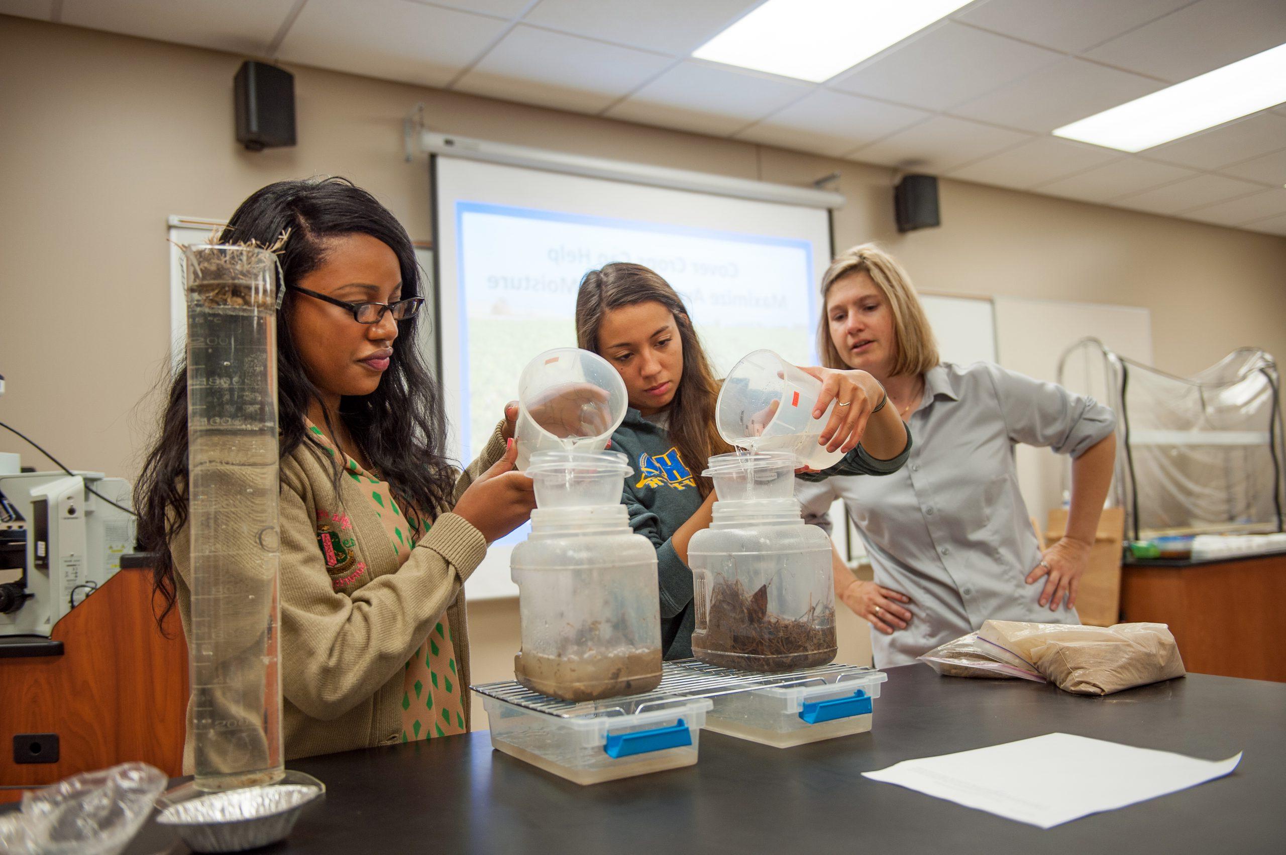 两名学生和一名教师在课堂上进行土壤和水的实验.